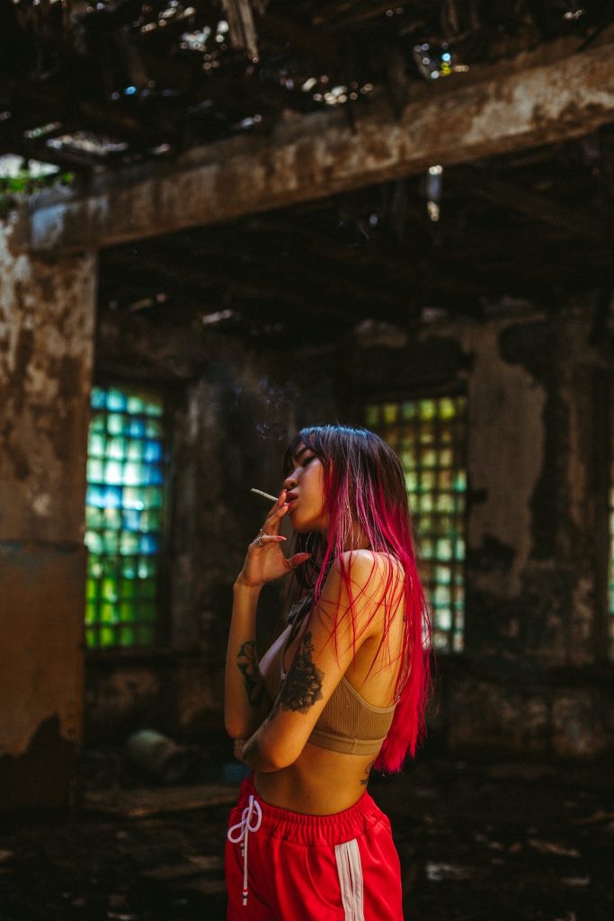 Photo by Ivan Babydov: https://www.pexels.com/photo/woman-with-pink-hair-in-sportswear-smoking-in-ruined-building-7787670/